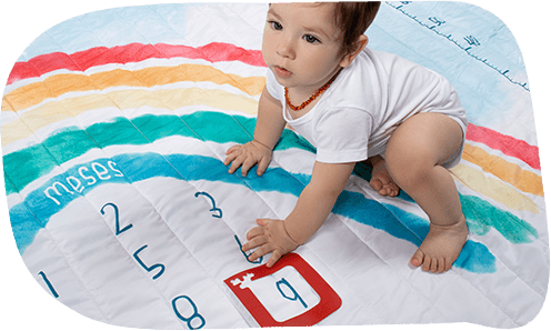 Bebê sentado sobre tapete mesversário arco-íris com marcador de mês